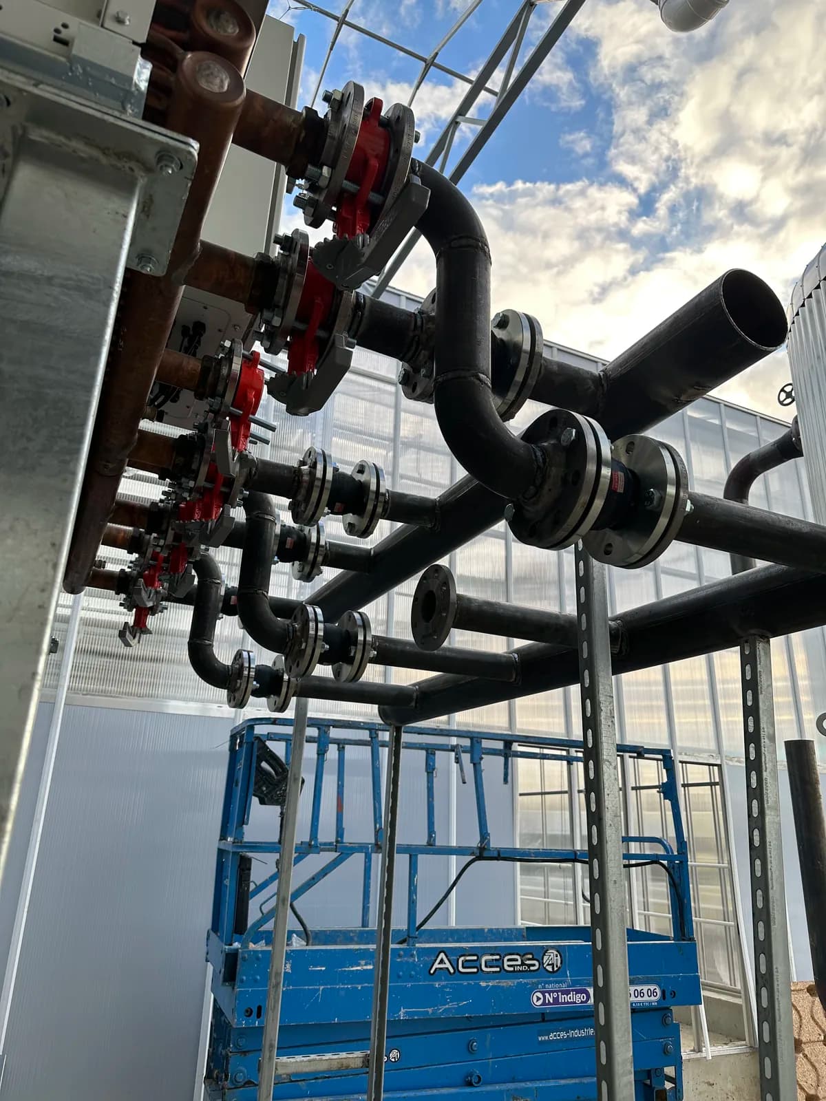 Collecteur de tuyauterie acier sur supports, installé en extérieur sous un ciel bleu
