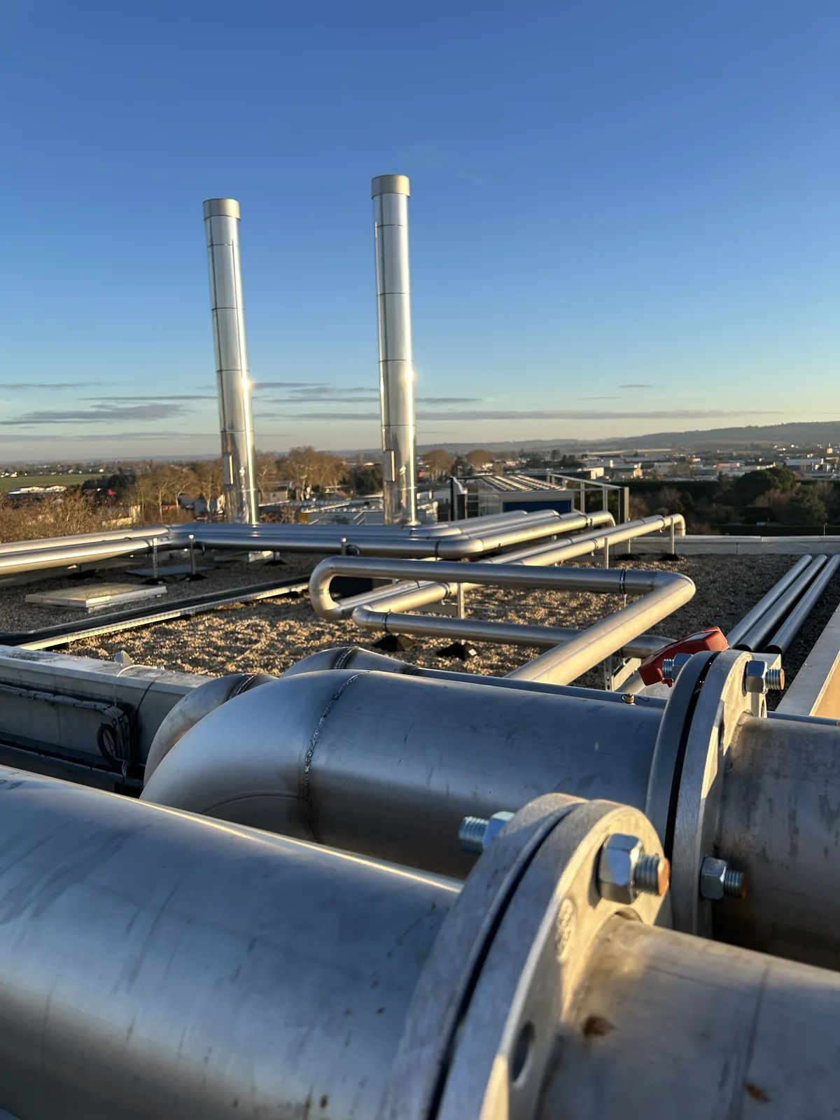 Lignes de distribution calorifugées et cheminées inox en extérieur, ciel bleu
